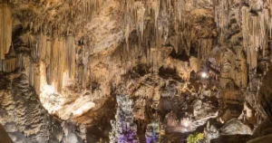 Interior iluminado de la Cueva de Nerja con grandes formaciones de estalactitas