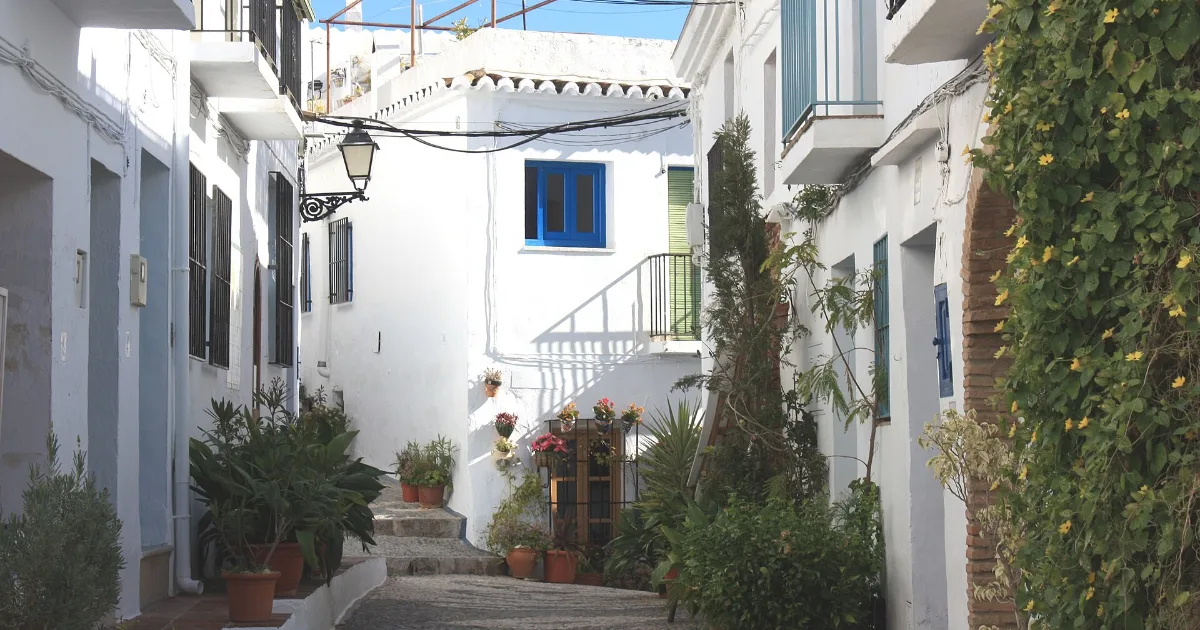 Calle empinada del barrio morisco de Frigiliana con macetas y fachadas encaladas